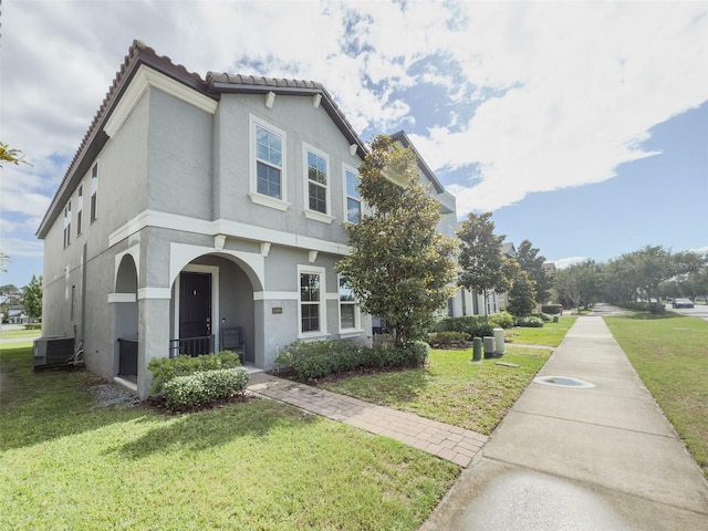 view of front of property with stucco siding, a front lawn, central AC unit, and a tile roof