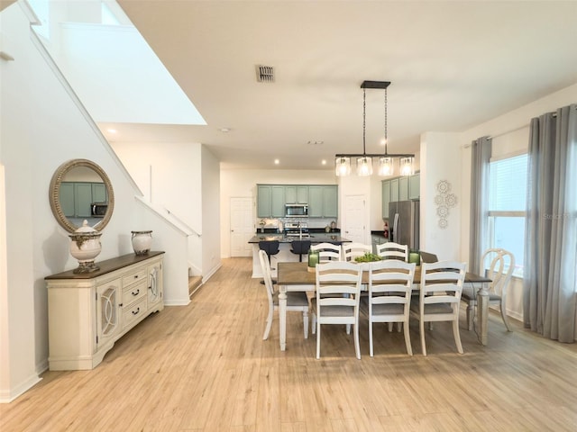 dining area with light wood finished floors, recessed lighting, stairs, and baseboards