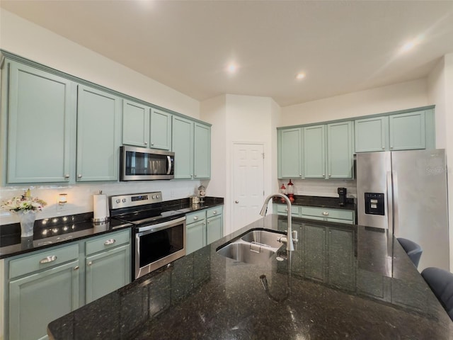 kitchen featuring appliances with stainless steel finishes, a sink, dark stone counters, and recessed lighting