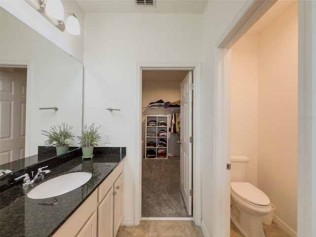 bathroom featuring toilet, a spacious closet, vanity, and tile patterned flooring
