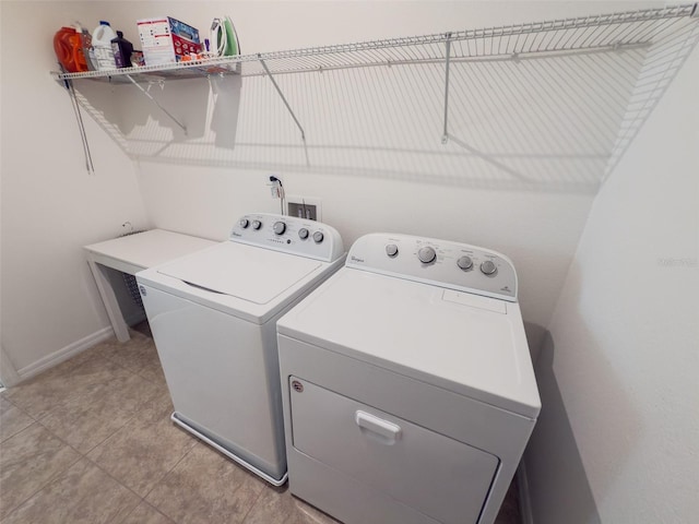 laundry room featuring washing machine and clothes dryer, baseboards, and light tile patterned floors
