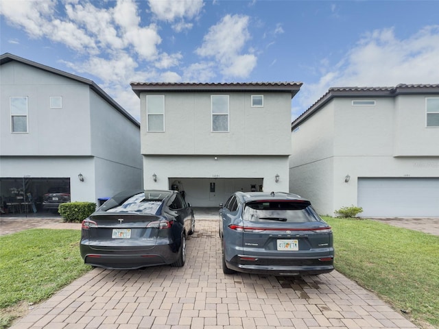 view of front facade with an attached garage, decorative driveway, stucco siding, and a front yard