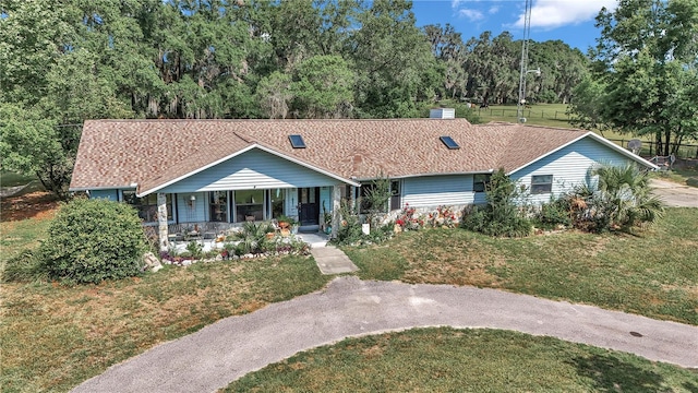 view of front of house with covered porch, a front lawn, and view of wooded area
