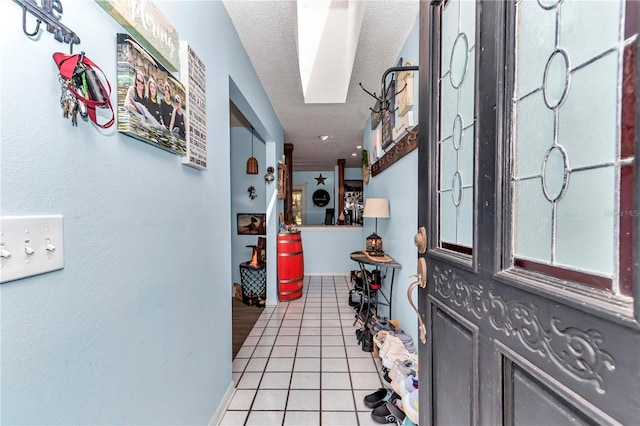 entrance foyer with light tile patterned flooring, a skylight, a textured ceiling, and baseboards