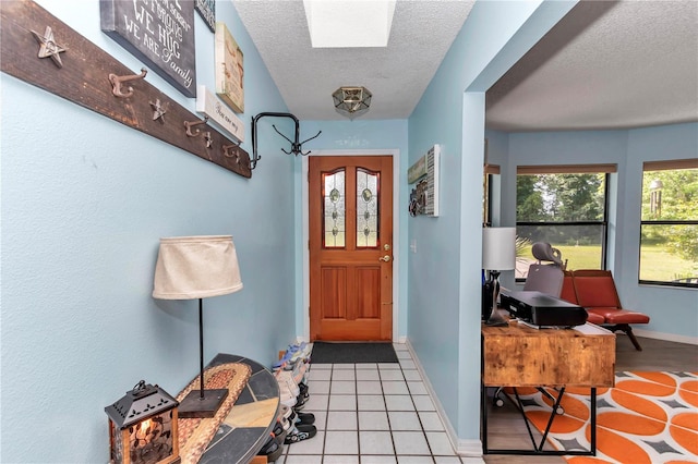 tiled foyer entrance with a textured ceiling and baseboards