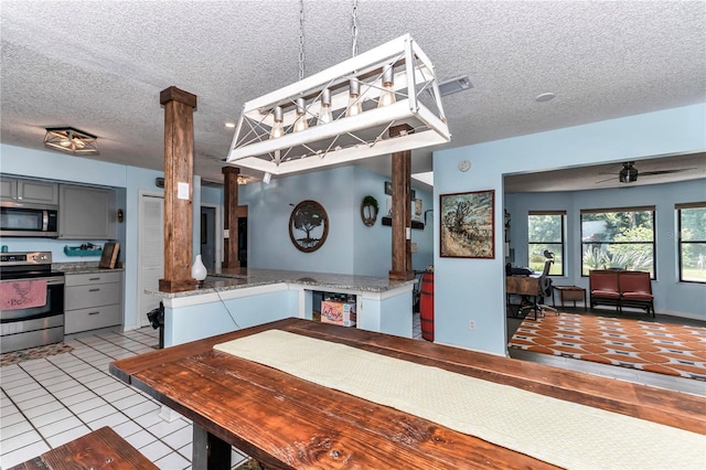 dining room with ornate columns, a textured ceiling, a ceiling fan, and light tile patterned flooring