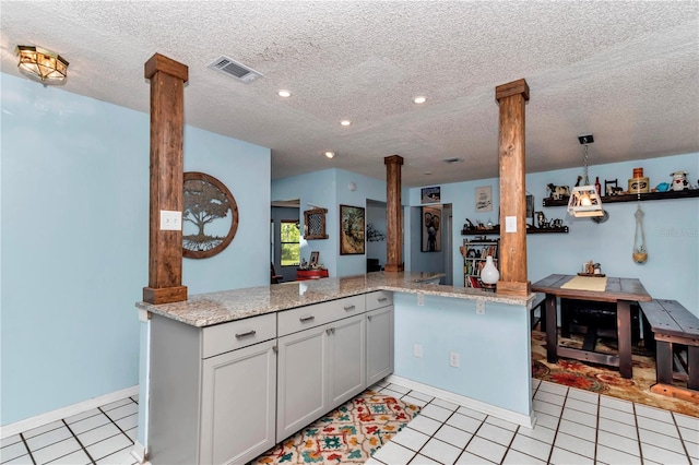 kitchen featuring decorative columns, light tile patterned floors, a textured ceiling, light stone countertops, and recessed lighting