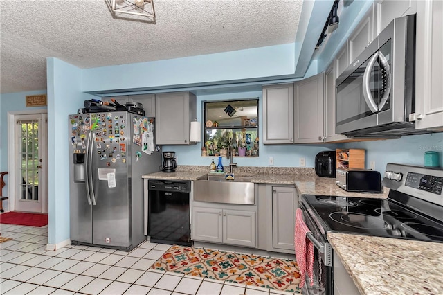 kitchen with appliances with stainless steel finishes, gray cabinets, a sink, a textured ceiling, and light tile patterned flooring