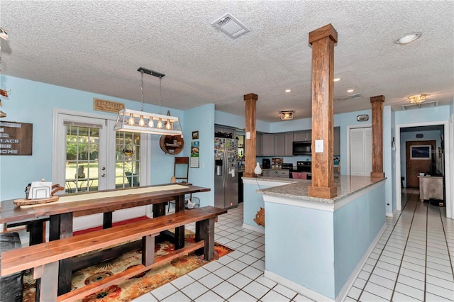 kitchen with decorative columns, appliances with stainless steel finishes, a textured ceiling, light tile patterned flooring, and a peninsula