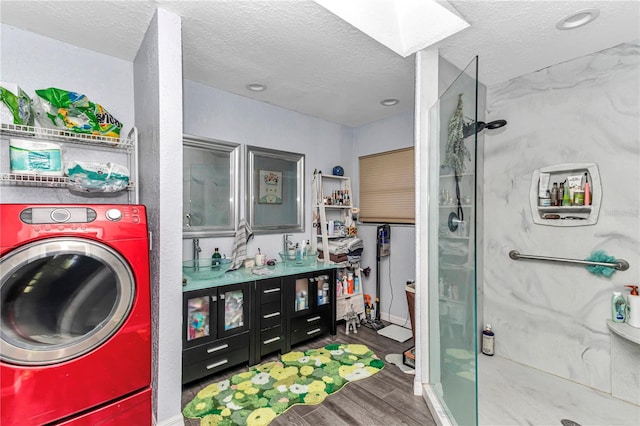full bathroom featuring washer / clothes dryer, wood finished floors, a shower stall, a skylight, and a textured ceiling