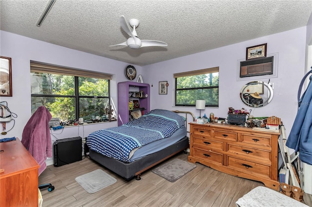 bedroom with light wood finished floors, a textured ceiling, and a ceiling fan