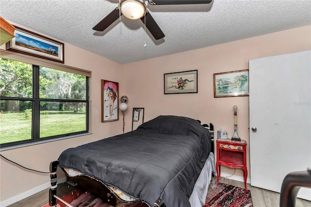 bedroom featuring wood finished floors, baseboards, a textured ceiling, and ceiling fan