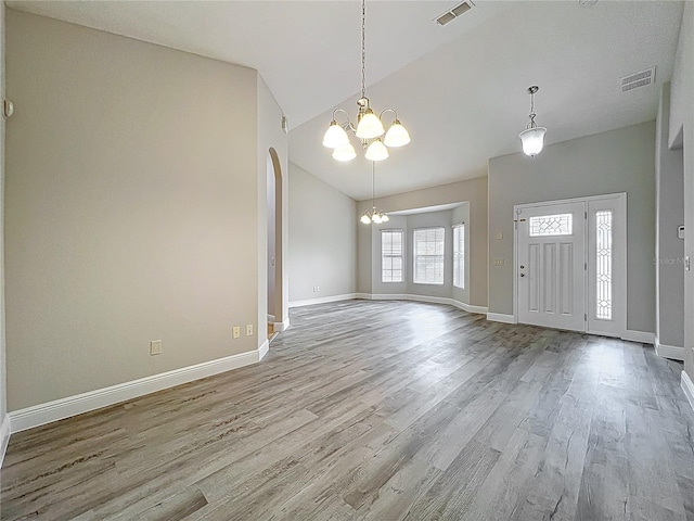 foyer with a chandelier, visible vents, wood finished floors, and vaulted ceiling