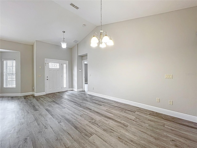 foyer entrance featuring a notable chandelier, baseboards, visible vents, and wood finished floors