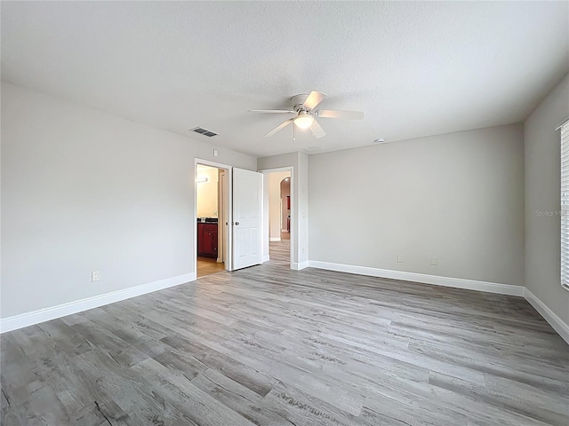 unfurnished room featuring a ceiling fan, baseboards, light wood finished floors, and visible vents