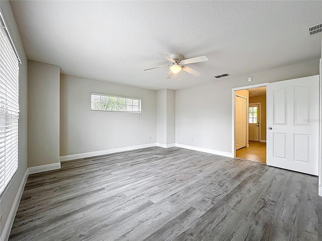 unfurnished room with visible vents, wood finished floors, baseboards, and ceiling fan