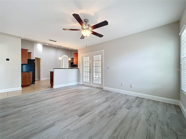 unfurnished living room featuring visible vents, baseboards, ceiling fan, arched walkways, and light wood-style floors