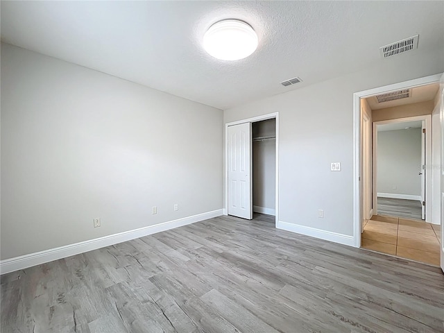 unfurnished bedroom with baseboards, visible vents, and wood finished floors