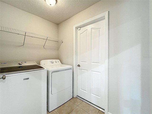 washroom featuring light tile patterned floors, a textured ceiling, laundry area, and independent washer and dryer