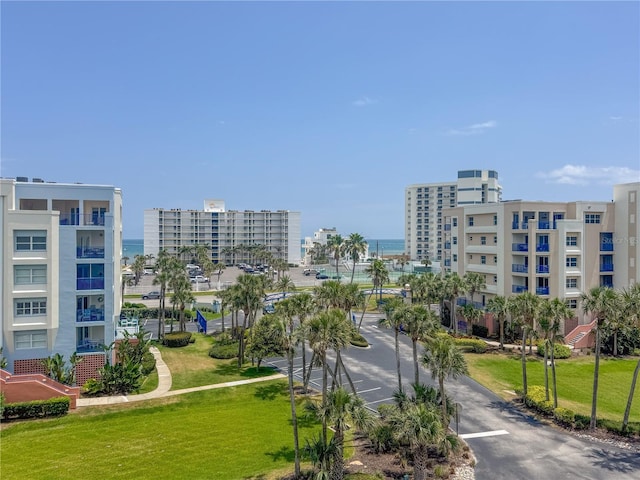 surrounding community featuring uncovered parking, a view of city, and a lawn