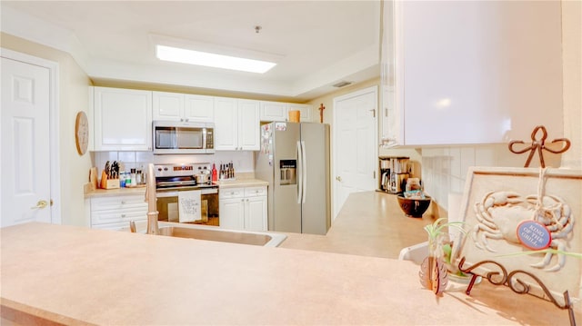 kitchen with a sink, stainless steel appliances, white cabinetry, and light countertops