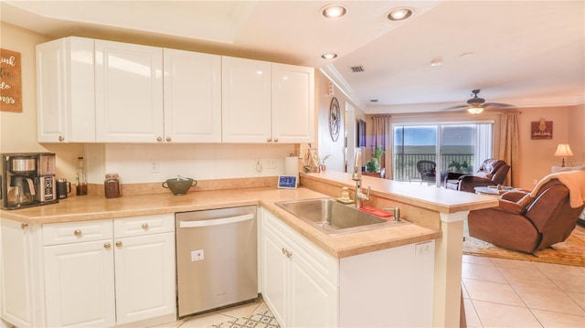 kitchen with a peninsula, light tile patterned floors, a sink, open floor plan, and stainless steel dishwasher
