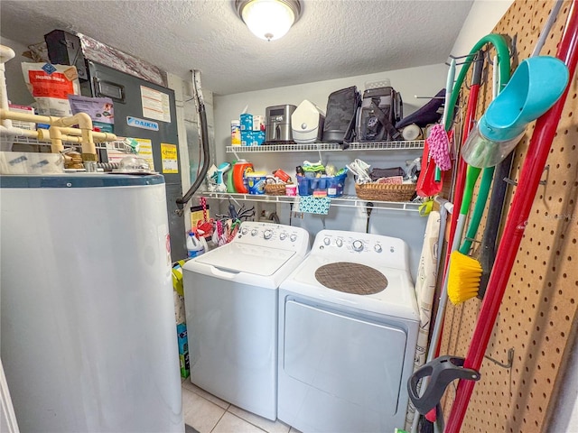 washroom with water heater, a textured ceiling, laundry area, washer and dryer, and tile patterned floors