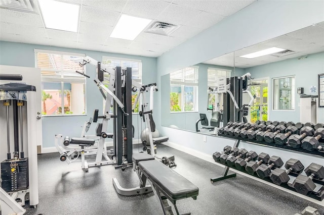 workout area with baseboards, a drop ceiling, visible vents, and a wealth of natural light