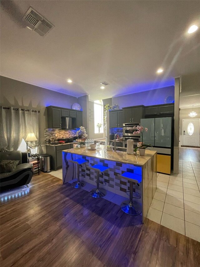 447 Cadiz Loop, Davenport, FL 33837 - kitchen featuring freestanding refrigerator, light wood-type flooring, visible vents, and a kitchen bar