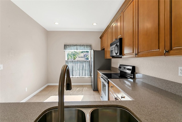 2975 White Cedar Cir, Kissimmee, FL 34741 - kitchen with stainless steel electric range oven, black microwave, brown cabinets, light tile patterned floors, and recessed lighting