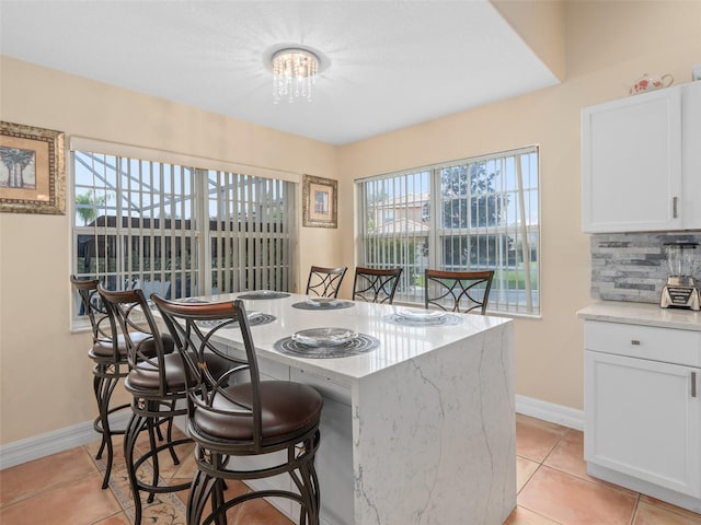 kitchen with a breakfast bar area, baseboards, light tile patterned floors, and a healthy amount of sunlight