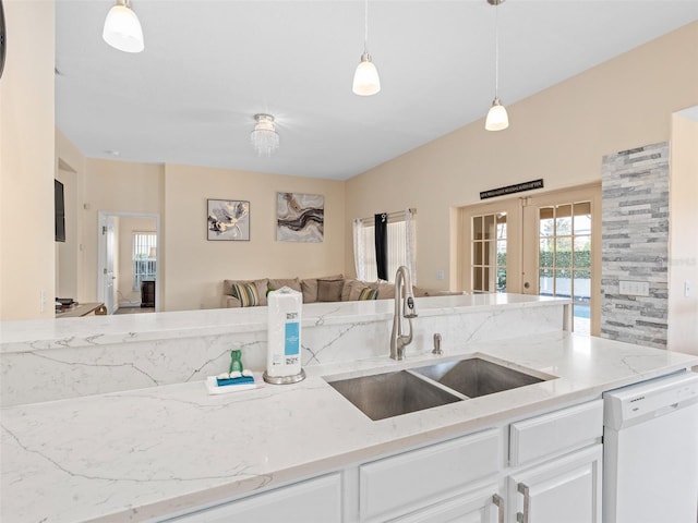 kitchen with french doors, a sink, open floor plan, light stone countertops, and white dishwasher