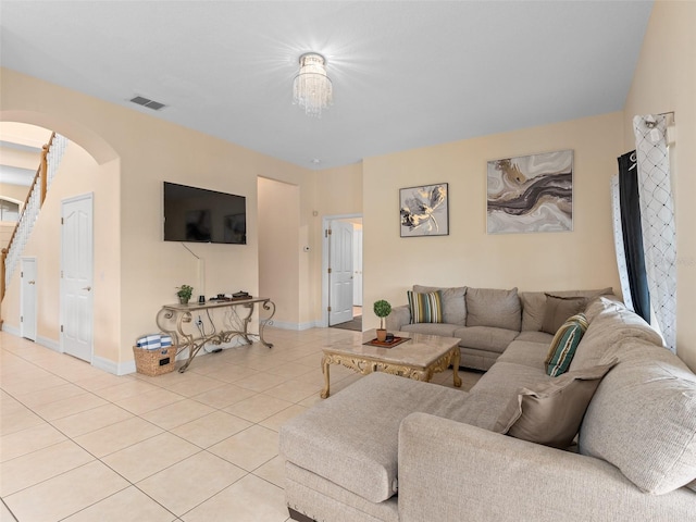living room featuring light tile patterned floors, visible vents, baseboards, and arched walkways