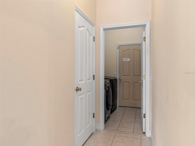 corridor with washing machine and clothes dryer, baseboards, and light tile patterned floors