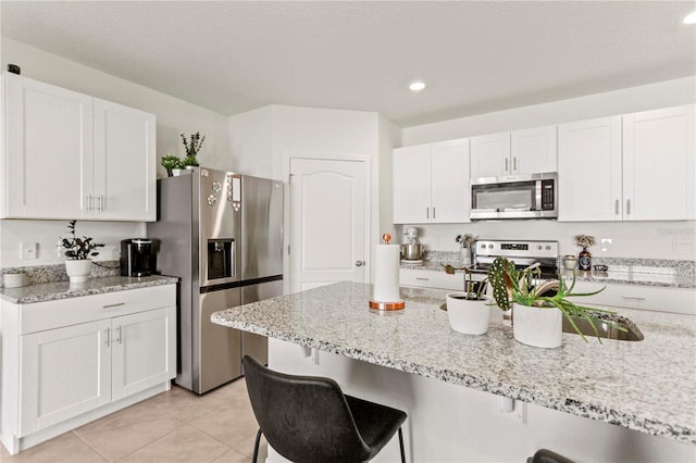 1975 Cacutta Way, Kissimmee, FL 34744 - kitchen with appliances with stainless steel finishes, a breakfast bar area, white cabinetry, and recessed lighting
