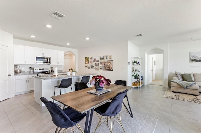 1975 Cacutta Way, Kissimmee, FL 34744 - dining area with arched walkways, recessed lighting, light tile patterned floors, and a textured ceiling