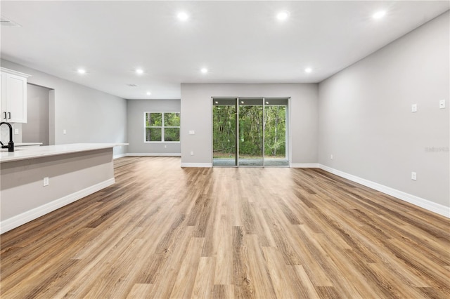 unfurnished living room with recessed lighting, light wood-style floors, and baseboards