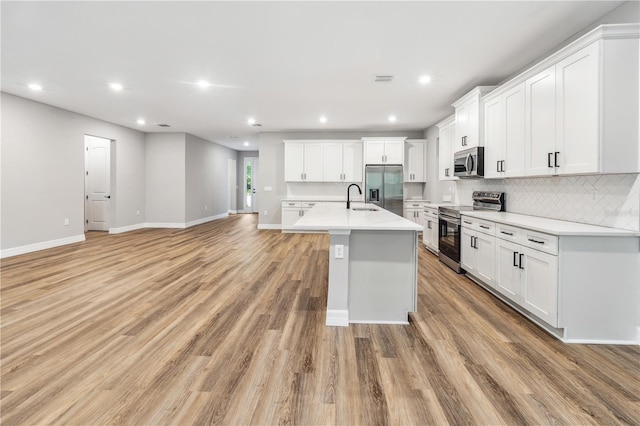 kitchen with appliances with stainless steel finishes, a sink, backsplash, white cabinetry, and recessed lighting