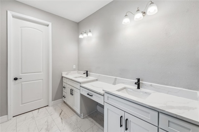 bathroom with marble finish floors, vanity, and baseboards