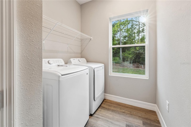laundry area with washing machine and dryer, wood finished floors, and baseboards