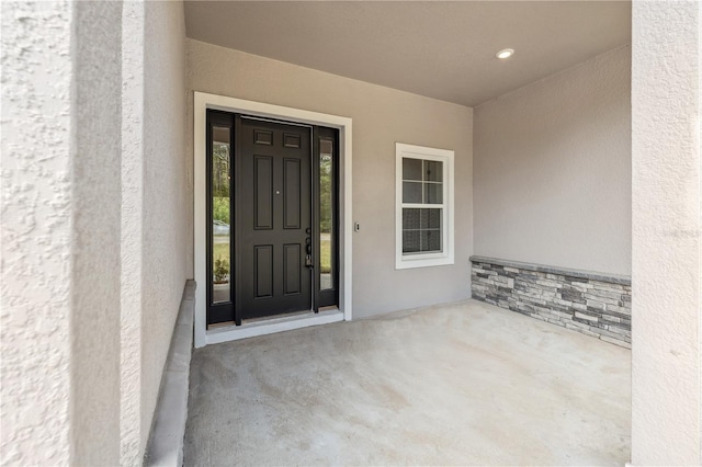 view of exterior entry featuring stucco siding and stone siding