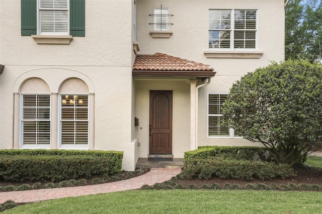 property entrance with stucco siding and a tiled roof