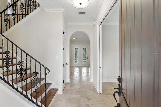 foyer with arched walkways, baseboards, crown molding, stone tile floors, and stairway