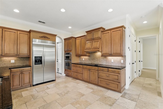 kitchen with stainless steel appliances, brown cabinetry, stone tile flooring, recessed lighting, and backsplash