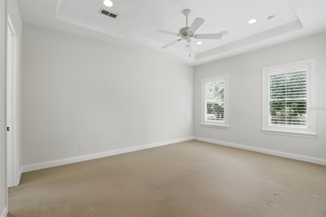 unfurnished room featuring a raised ceiling, light colored carpet, baseboards, recessed lighting, and ceiling fan