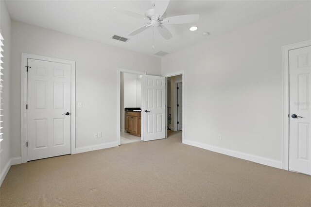 unfurnished bedroom featuring light colored carpet, baseboards, ensuite bath, and a ceiling fan