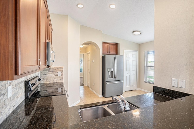 3319 Thistledown Ln, Land O Lakes, FL 34638 - kitchen with stainless steel appliances, arched walkways, a sink, brown cabinetry, and dark stone counters