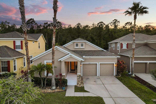view of front of house with concrete driveway, an attached garage, stucco siding, and a shingled roof