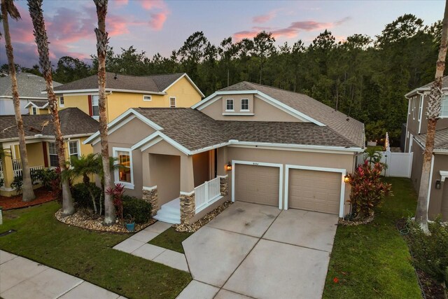 view of front facade featuring a shingled roof, stucco siding, driveway, and an attached garage