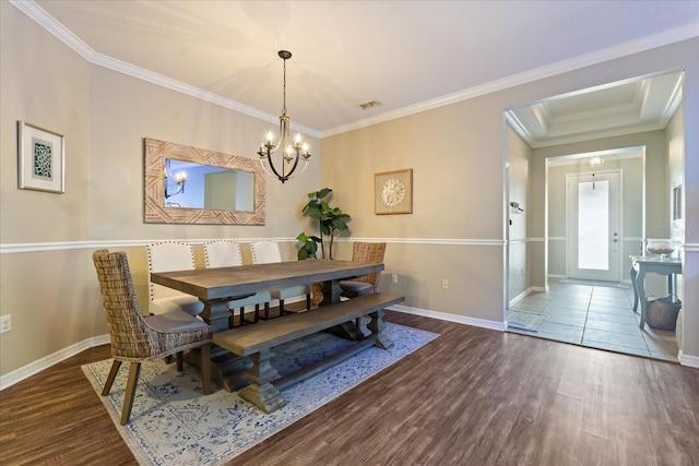 dining space with baseboards, a chandelier, crown molding, and wood finished floors